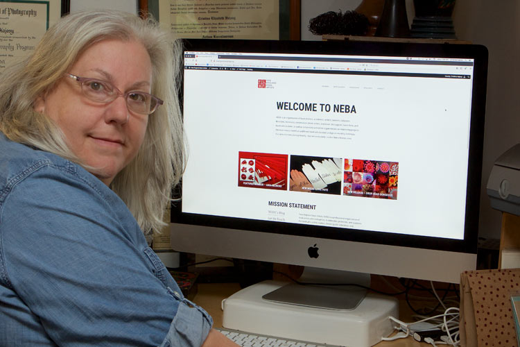 A photo of Cristina Hajosy at computer working on NEBA's website